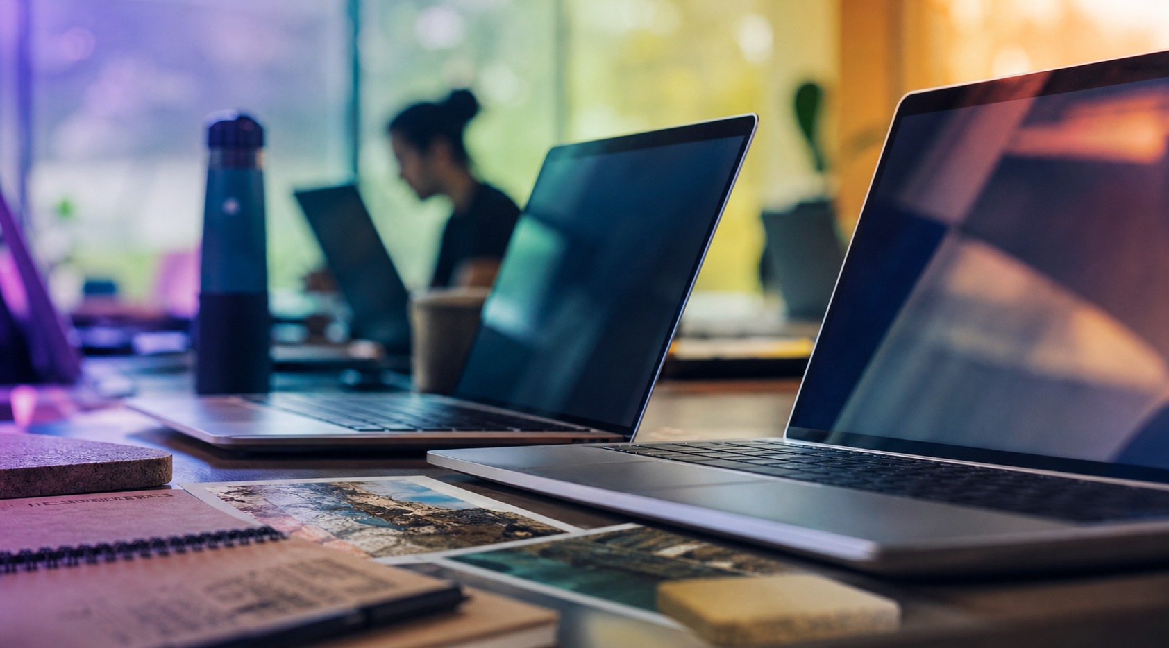Computadores em um ambiente corporativo com profissionais desfocados ao fundo